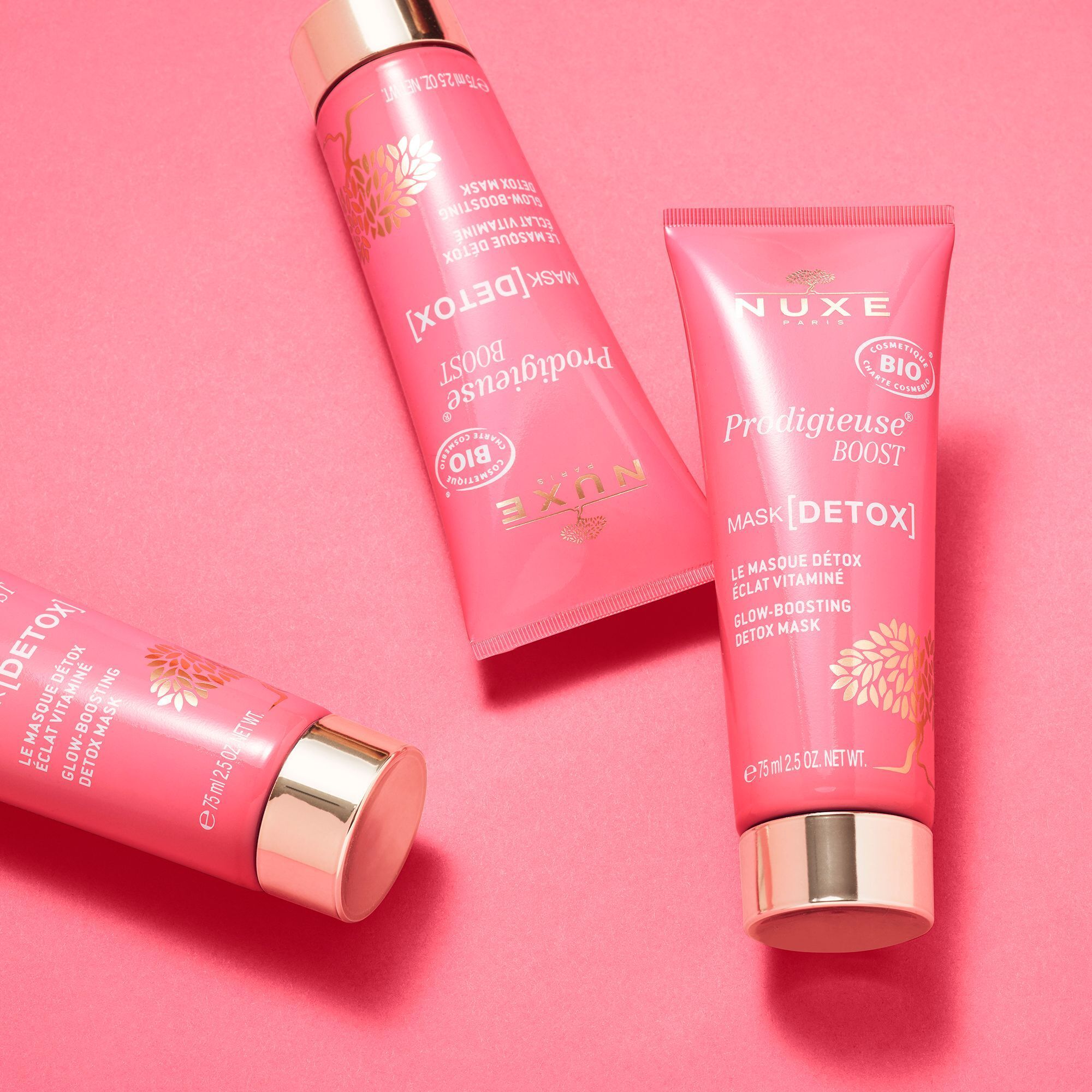 Drei rosa Tuben mit goldfarbenen Verschlüssen. Text: "NUXE Paris", "Prodigieuse Boost", "Mask [Detox]" und "Bio"-Siegel.