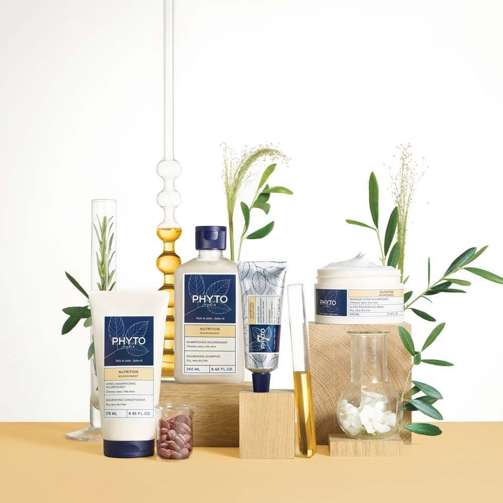 Verschiedene PHYTO PARIS Produkte auf Holzblöcken und in Glasbehältern. Produkte: Shampoo, Maske, Creme, Serum. Pflanzen und Laborglas.