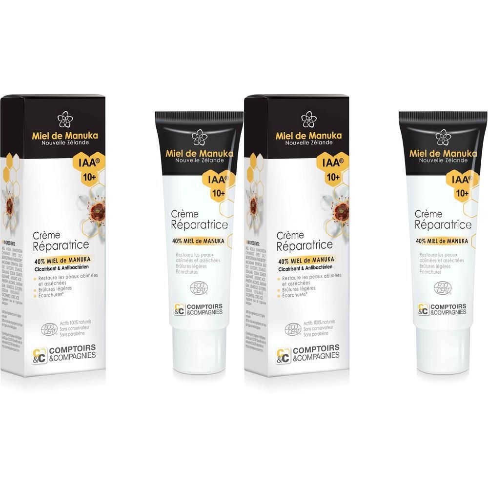 Creme-Tube und Verpackung. Schwarze Kappe, weißer Tubenkörper. Text: Crème Réparatrice, 40% Miel de Manuka, IAA 10+.