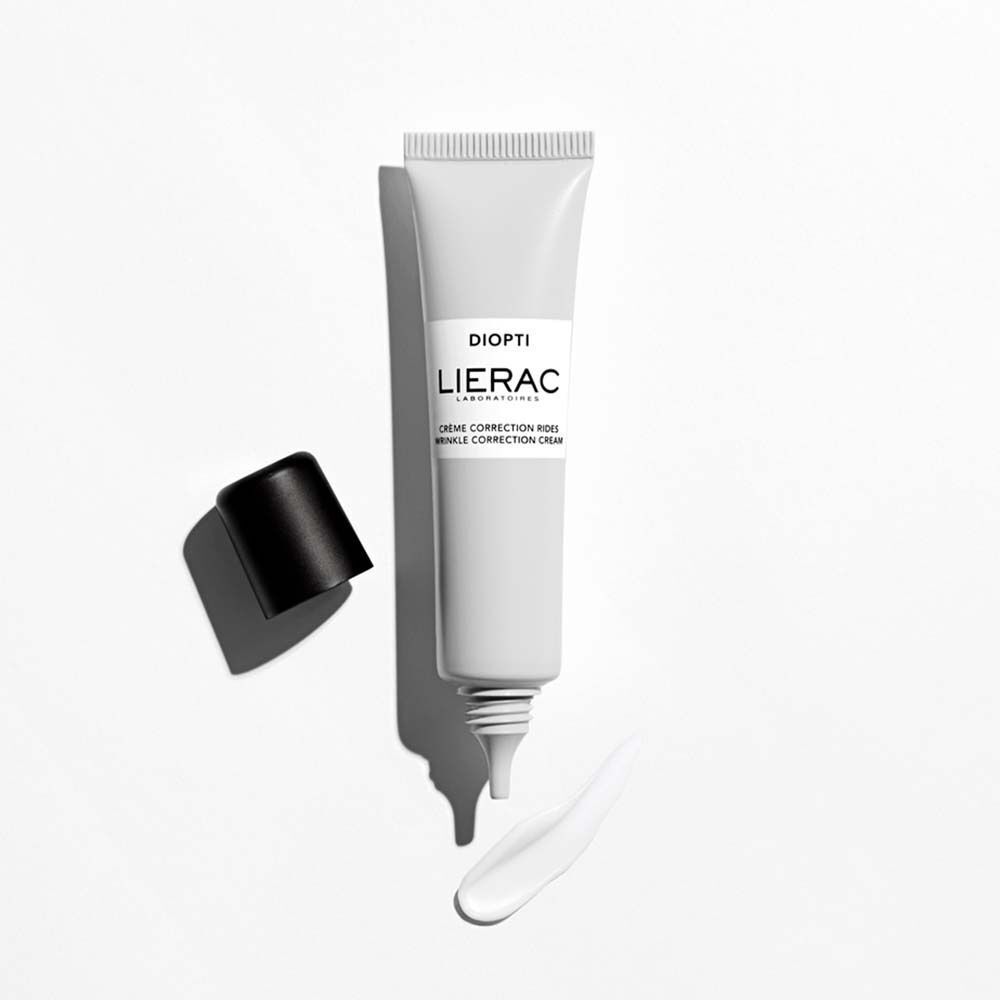 Eine Tube LIERAC Diopti Rides Augencreme, geöffnet. Schwarzer Deckel daneben. Creme-Strang. Text: DIOPTI, LIERAC, Crème Correction Rides, Wrinkle Correction Cream.