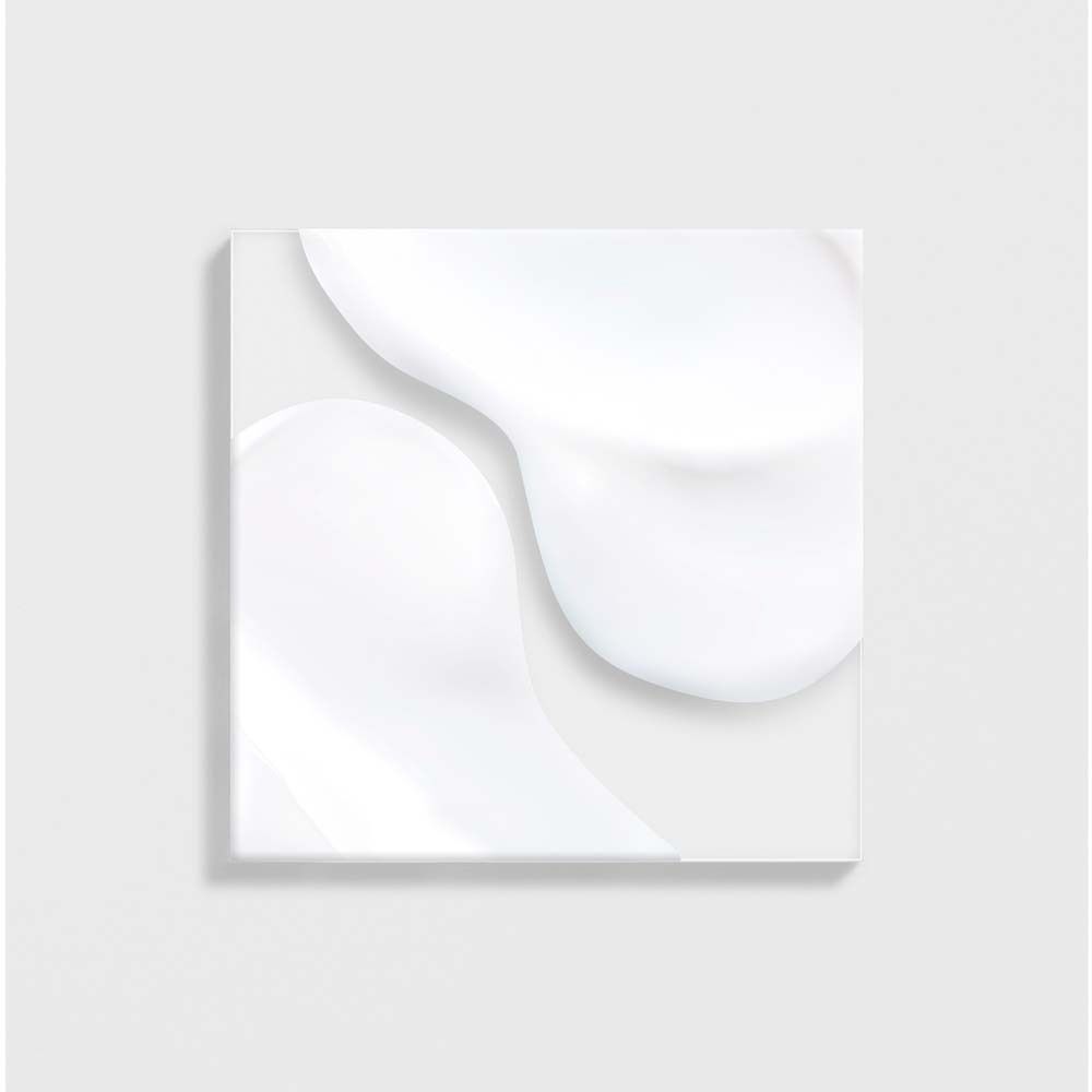 Nahaufnahme von weißen Creme-Schlieren auf quadratischem Untergrund. Keine Produktbezeichnung sichtbar.