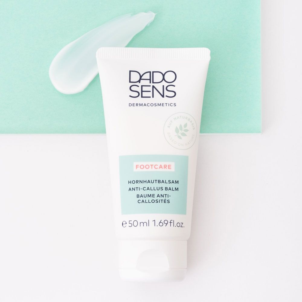 Weiße Tube DADO SENS Hornhautbalsam mit einem Klecks Balsam daneben.