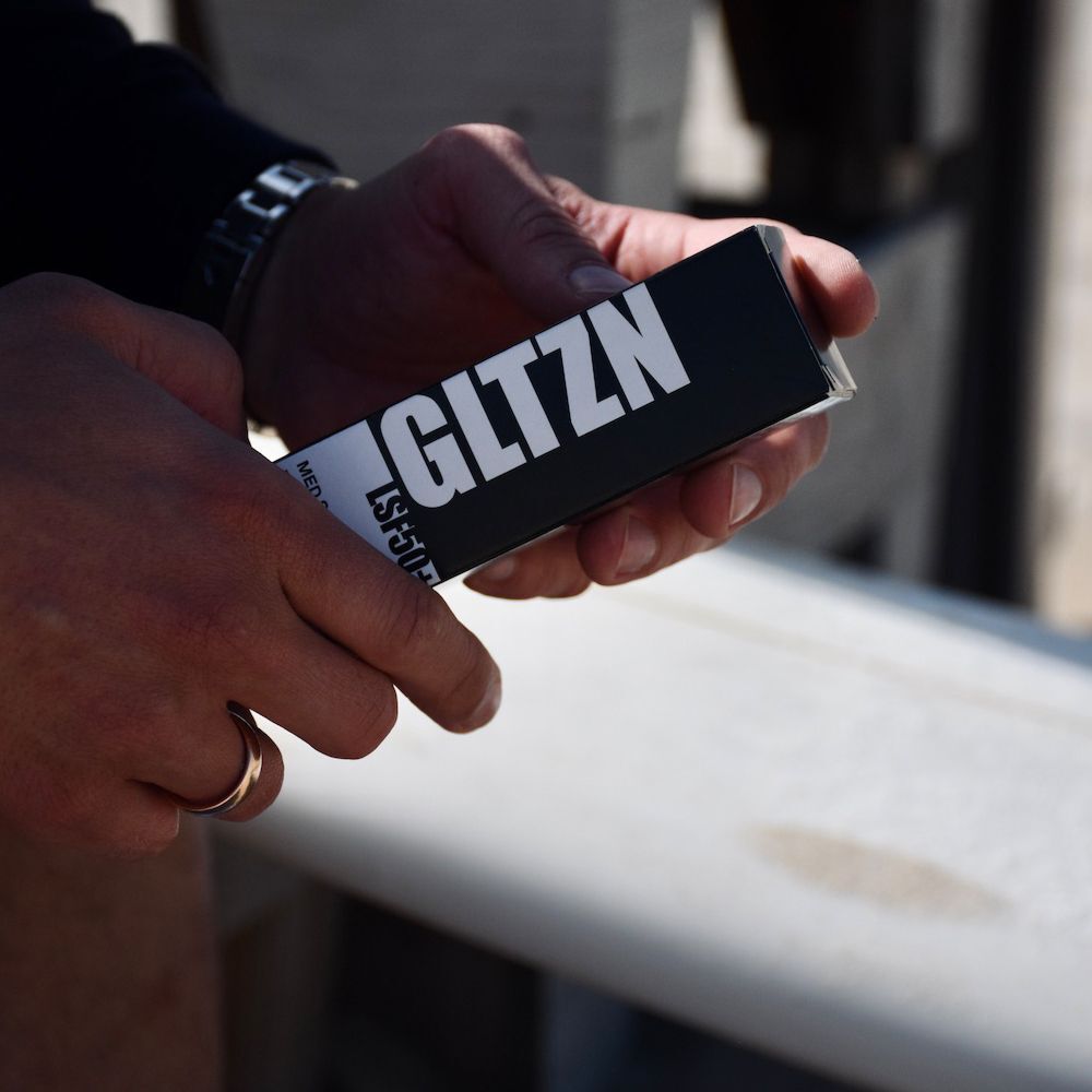 Hände halten die Verpackung der GLTZN MED Sonnencreme LSF 50+.