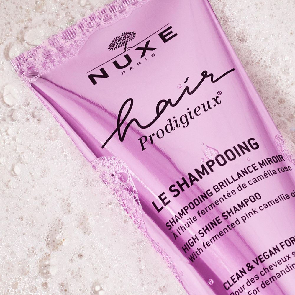 Rosa Tube Shampoo mit Schaum. Aufschrift: NUXE, Hair Prodigieux, Le Shampooing, High Shine Shampoo, Clean & Vegan Formula.