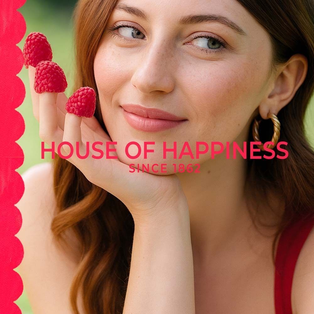 Frau mit Himbeeren auf den Fingern. Text: House of Happiness, Since 1862.