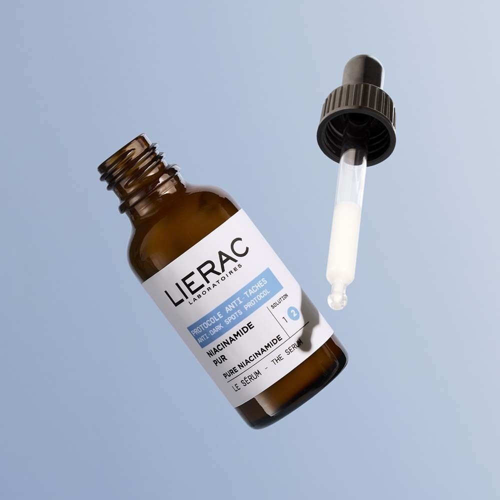Braune Glasflasche mit schwarzer Pipette. Pipette mit Serum. Etikett mit LIERAC, PROTOCOLE ANTI-TACHES und Niacinamid Pur.