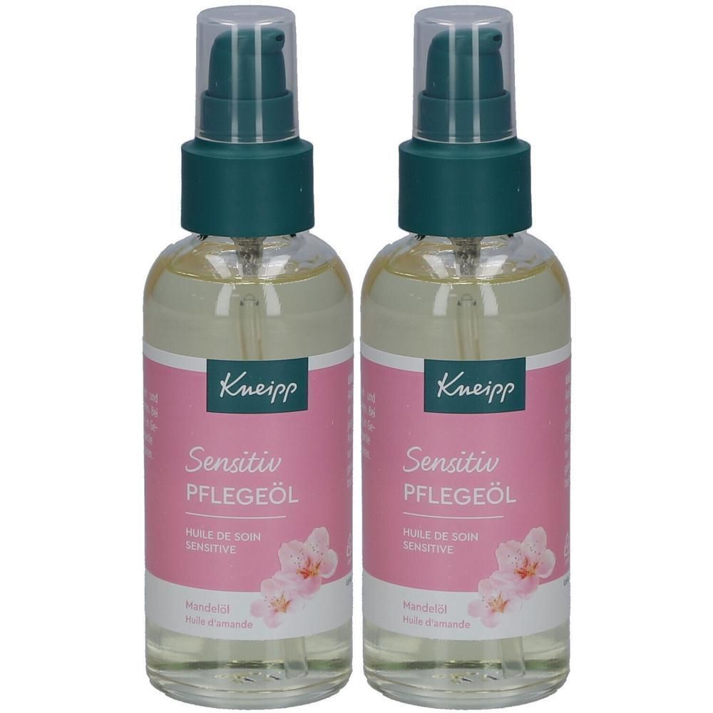 Zwei Flaschen mit grünem Pumpverschluss. Auf rosa Etiketten steht "Kneipp Sensitiv Pflegeöl". Blütenabbildung.