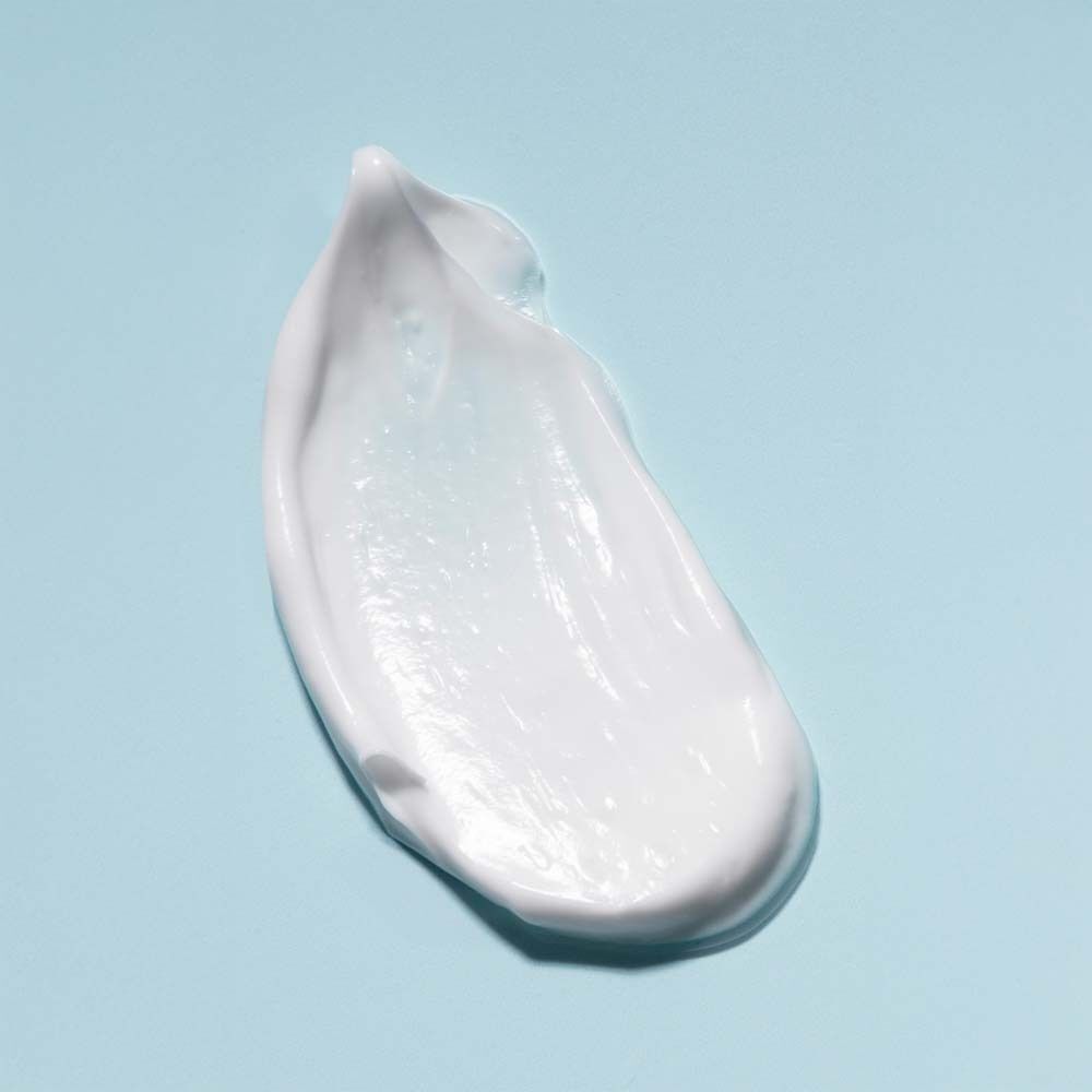 Ein Klecks Creme auf blauem Hintergrund. Weiße Creme, glatte Textur.