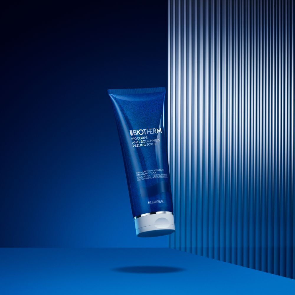 Blaue Tube BIOTHERM Biocorps Anti-Roughness Peeling Scrub vor blauem Hintergrund mit Streifen.