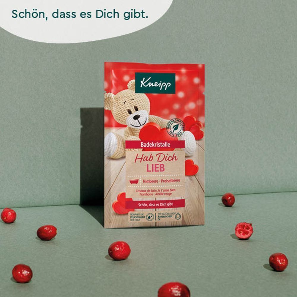 Kneipp® Badekristalle-Beutel mit Teddybär und Herzen. Text: Hab Dich Lieb, Himbeere-Preiselbeere. Rote Beeren liegen drumherum.