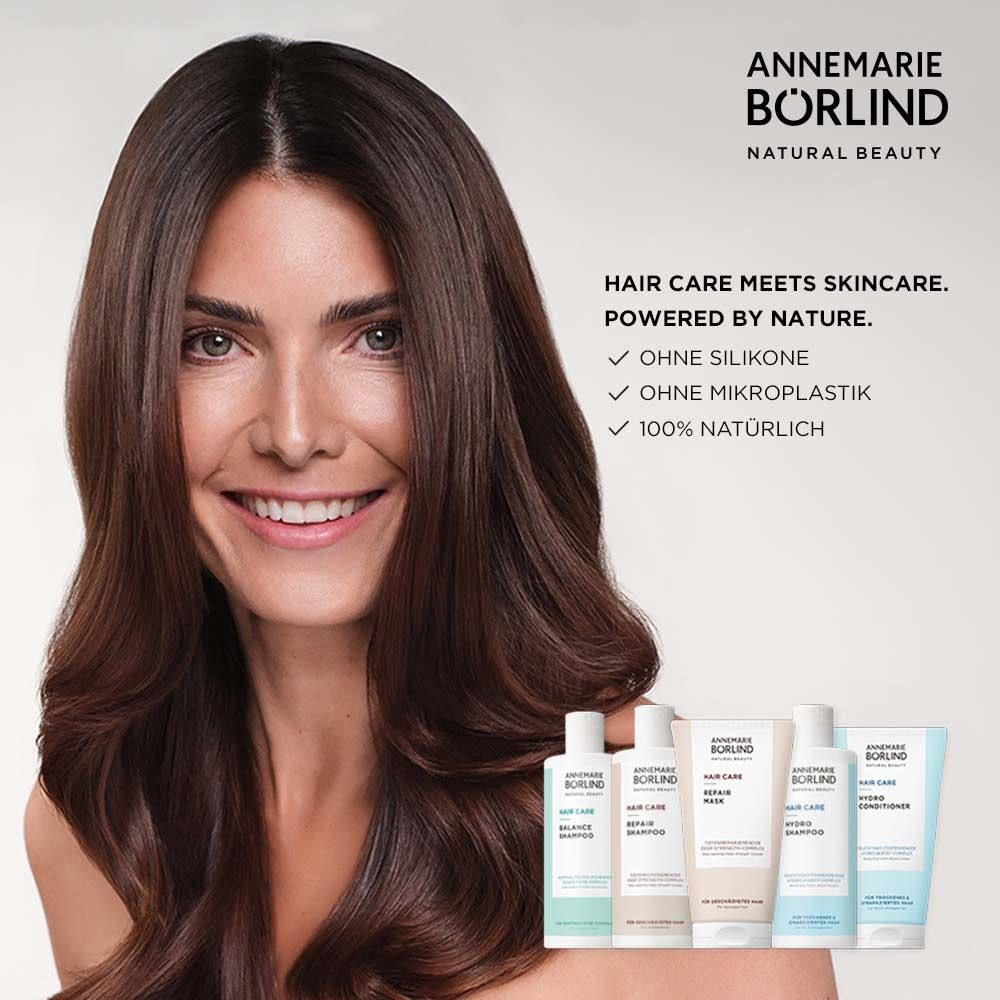 Frau mit langen, braunen Haaren. Produkte der Hair Care Serie im Hintergrund. Schriftzug: Hair Care meets Skincare.