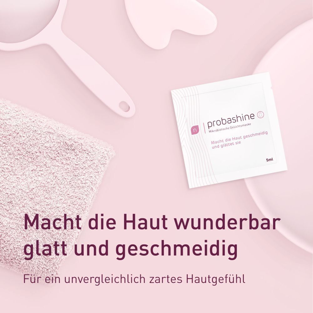 Gesichtsmaskenbeutel, Handtuch und Gesichtswerkzeuge auf rosa Hintergrund. Text: Macht die Haut wunderbar glatt.