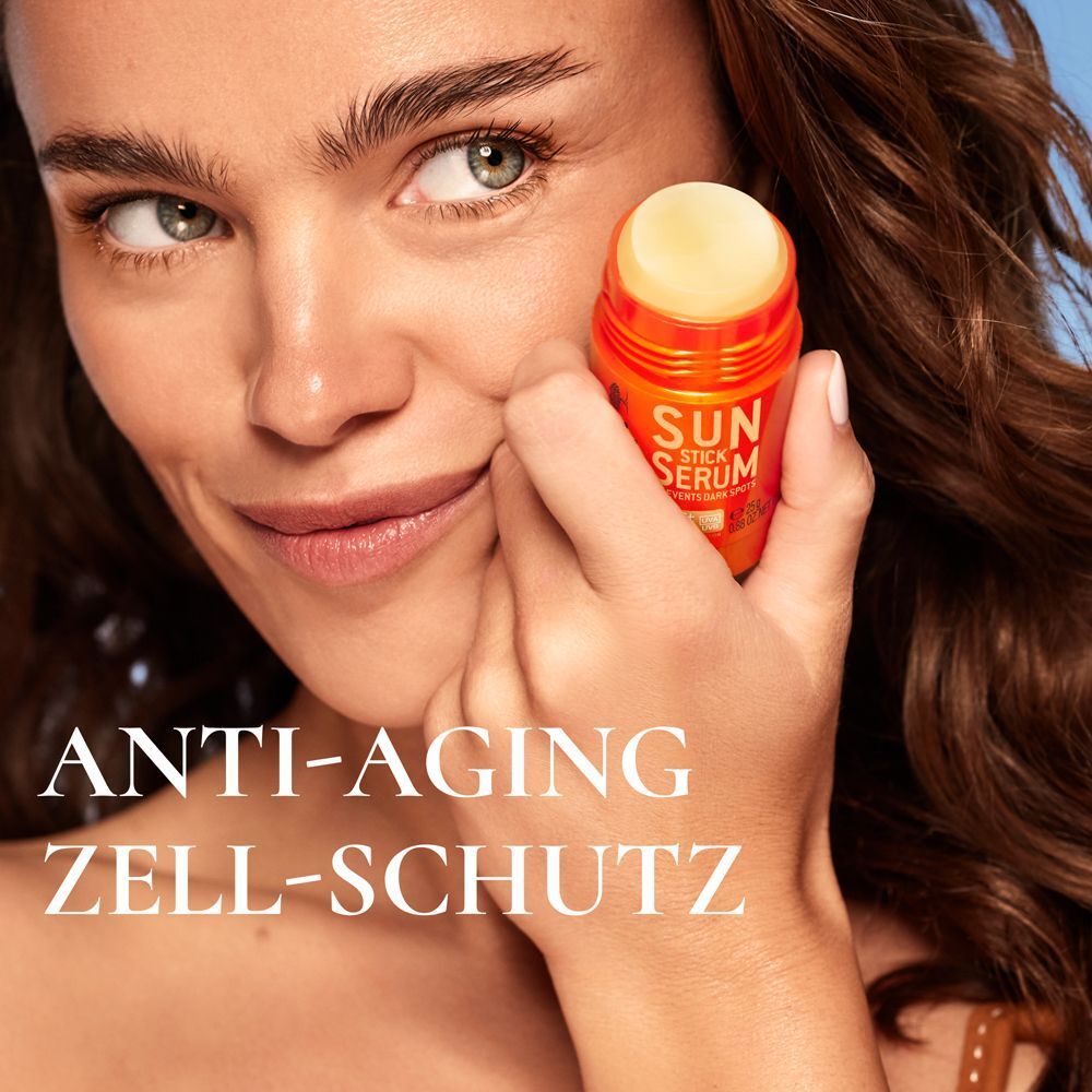 Eine Frau hält ein NUXE SUN Sonnenstick Serum LSF50+ an ihre Wange.