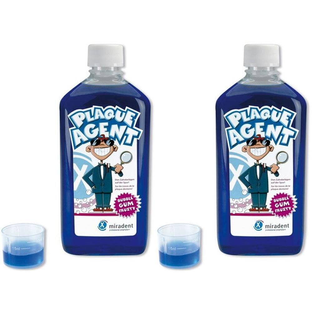 Zwei Flaschen mit blauer Flüssigkeit und weißem Deckel. Aufschrift: Plaque Agent. Zwei Messbecher mit blauer Flüssigkeit.