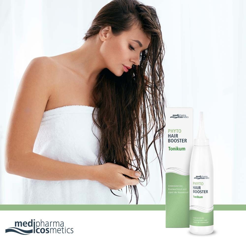 Frau mit nassem Haar und Phyto Hair Booster Tonikum. Flasche und Verpackung stehen daneben.