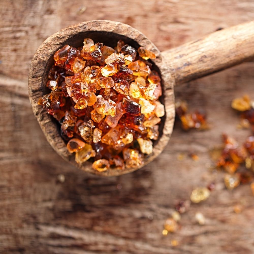 Holzlöffel mit Akaziengummi. Braune, kristallartige Stücke.