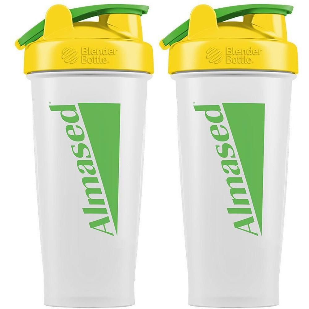 Zwei Shaker mit gelben Deckeln und grünen Klappverschlüssen. Aufschrift "Almased" in Grün. "Blender Bottle" Logo.