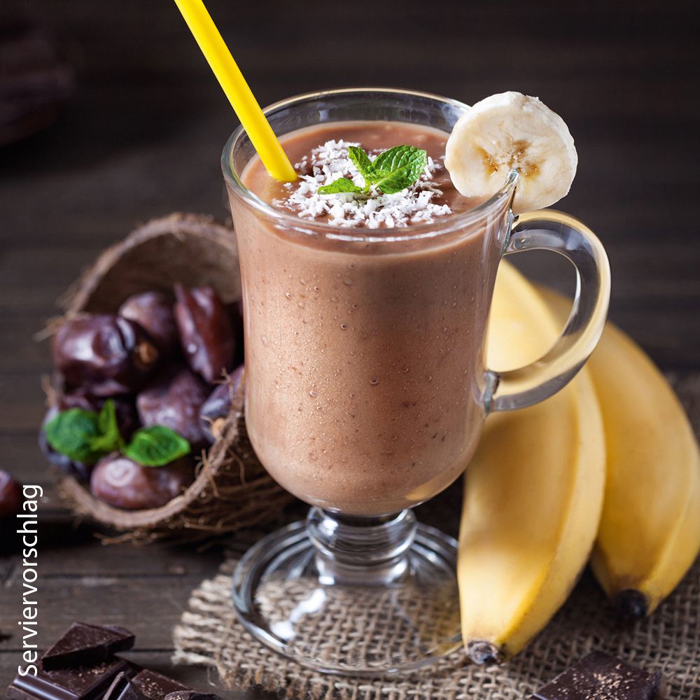 Schokoladen-Bananen-Shake in einem Glas mit Kokosnussschale, Datteln, Bananen und Schokolade.