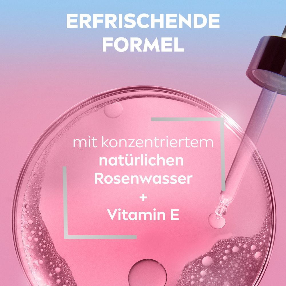 Eine Pipette tropft eine rosa Flüssigkeit in eine Petrischale mit konzentriertem Rosenwasser und Vitamin E.
