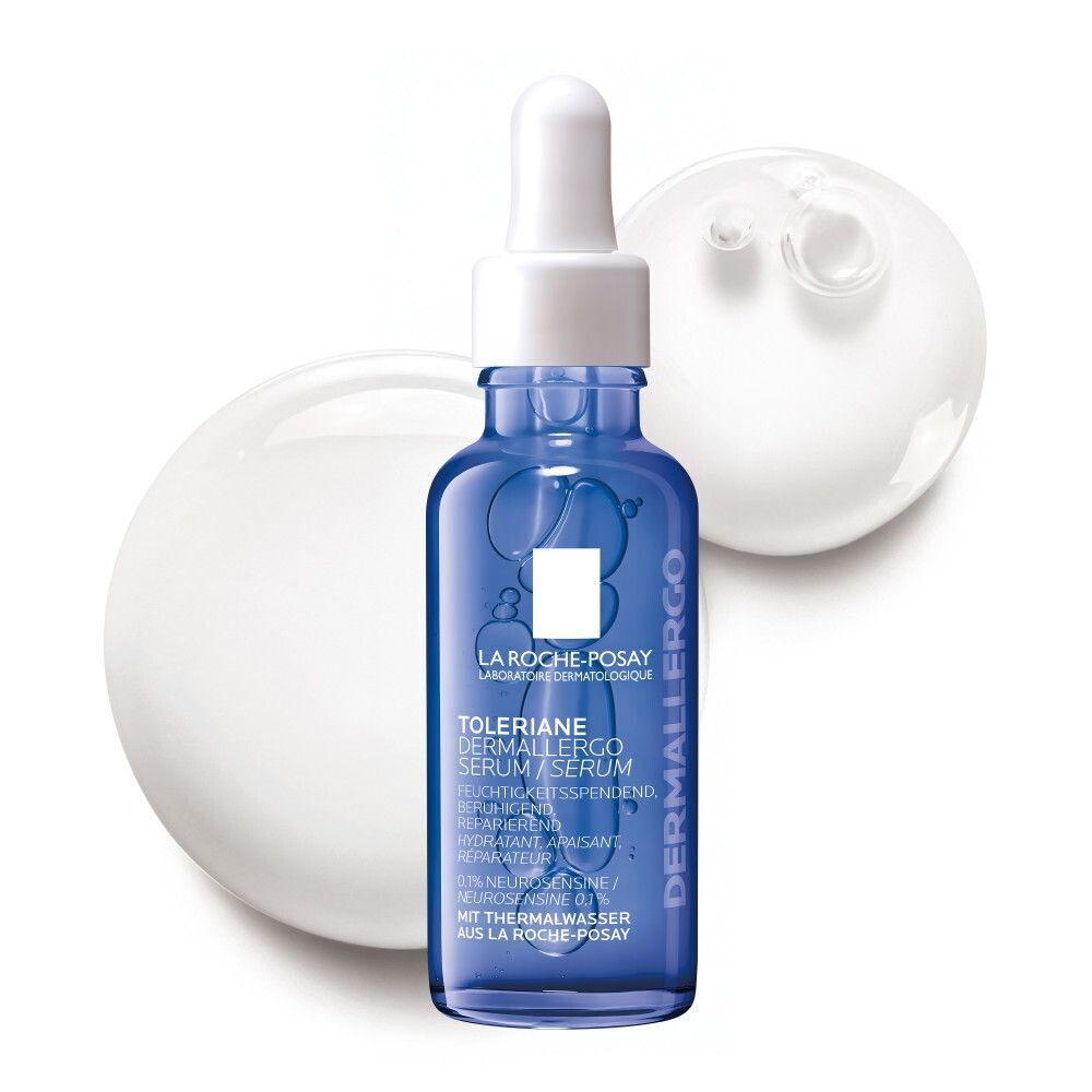 La Roche-Posay Toleriane Dermallergo Serum Flasche mit Pipettenverschluss, umgeben von weißen Flüssigkeitstropfen.