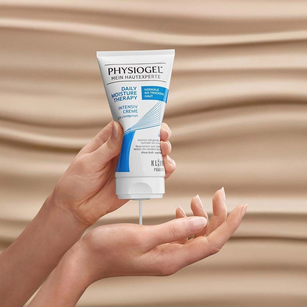 Hände halten eine Tube PHYSIogel Intensiv Creme, aus der weiße Creme austritt.