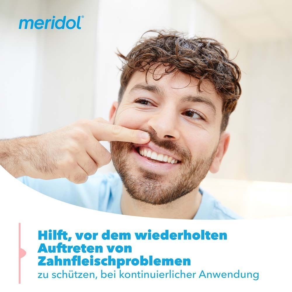 Mann zeigt auf seine Zähne; meridol Zahnpasta schützt vor wiederholten Zahnfleischproblemen.