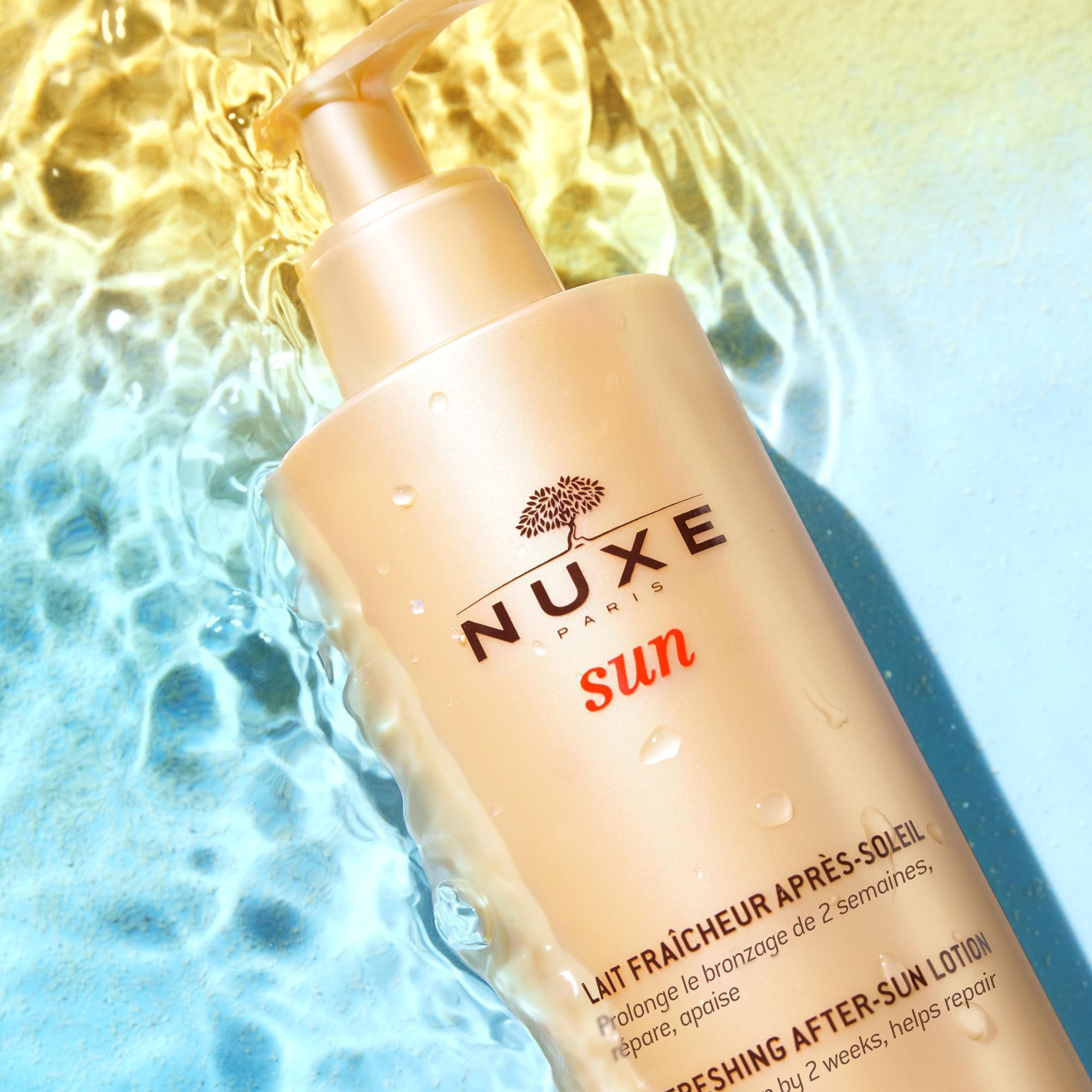 NUXE Sun After-Sun-Milch Flasche mit Pumpspender in Wasser. Gelbe Flasche mit Baum- und Sonnendesign.