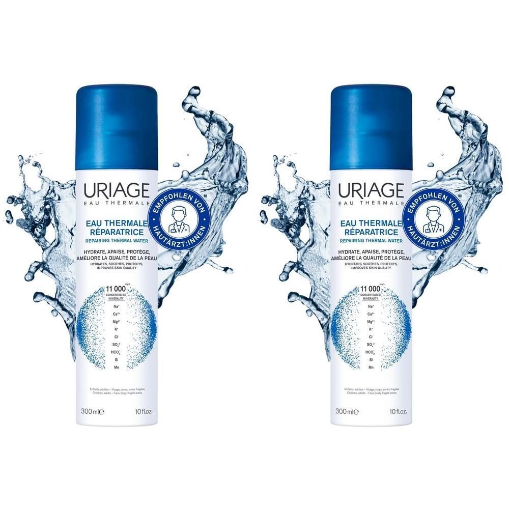 Zwei Uriage Eau Thermale Thermalwasser Sprühflaschen, umgeben von Wasserspritzern.