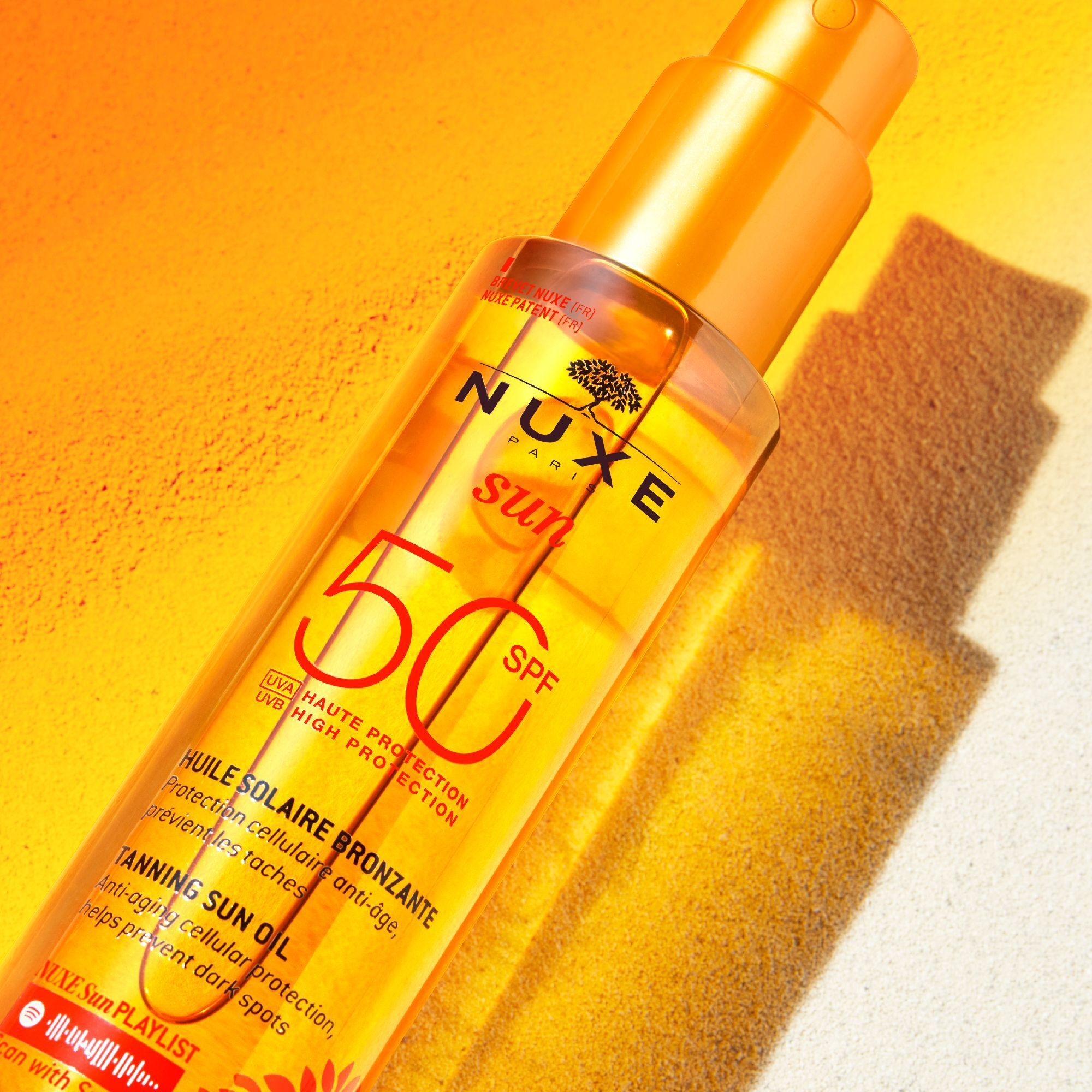 Flasche Nuxe Sun Sonnenöl LSF 50 mit hohem Schutz, mit Schattenwurf auf gelbem Hintergrund.