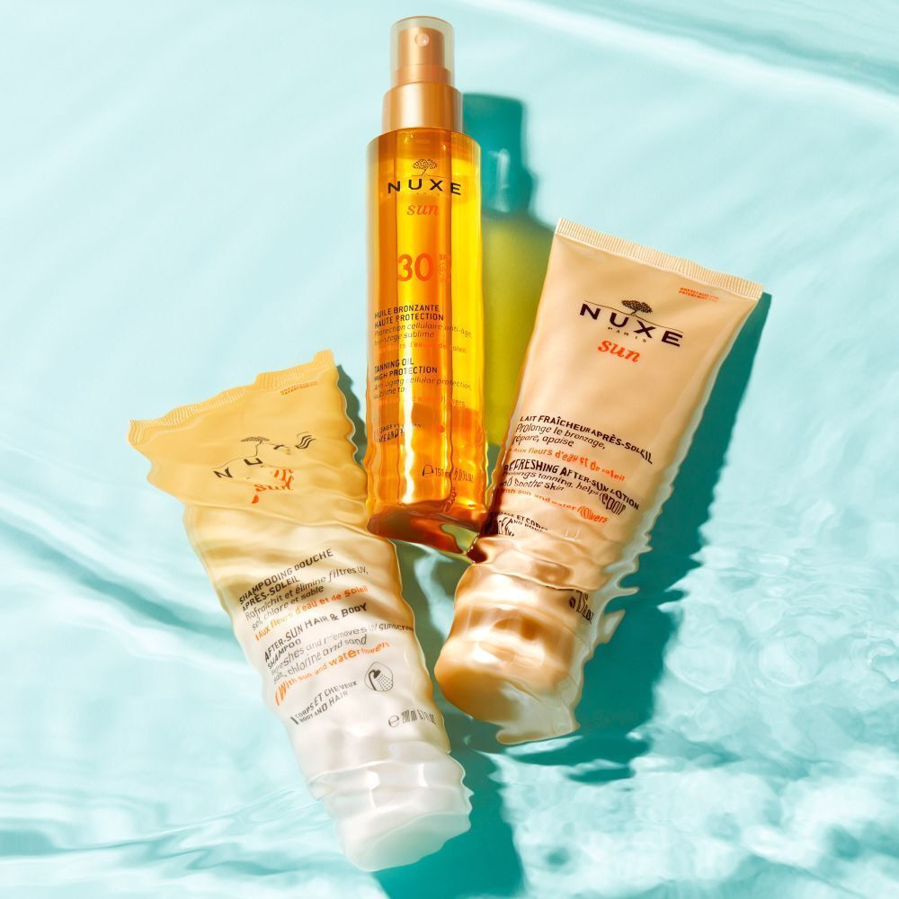 Drei NUXE Sun Produkte, darunter Sonnenmilch und ein Sonnenschutzöl, im Wasser.
