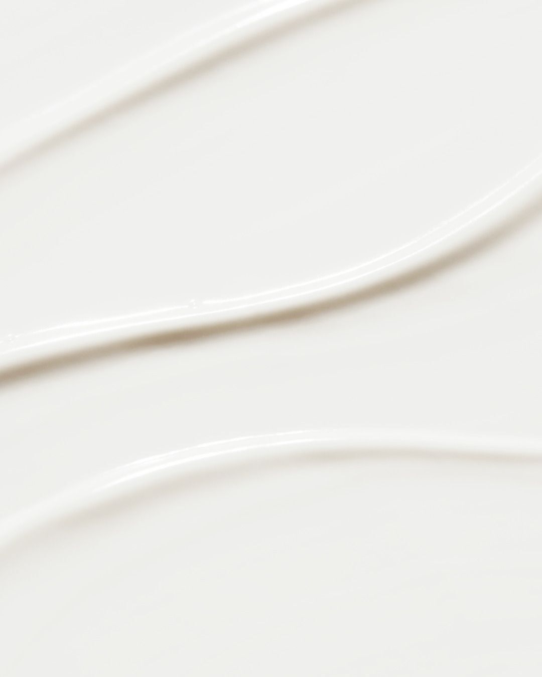 Weiße Creme-Textur mit wellenförmigen Spuren.