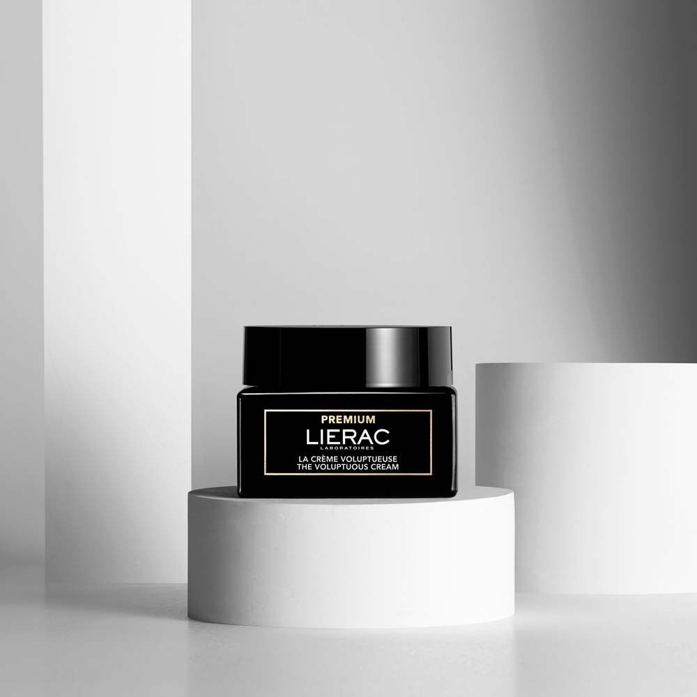 Ein LIERAC Premium Tiegel auf einem weißen Podest vor einem minimalistischen Hintergrund.