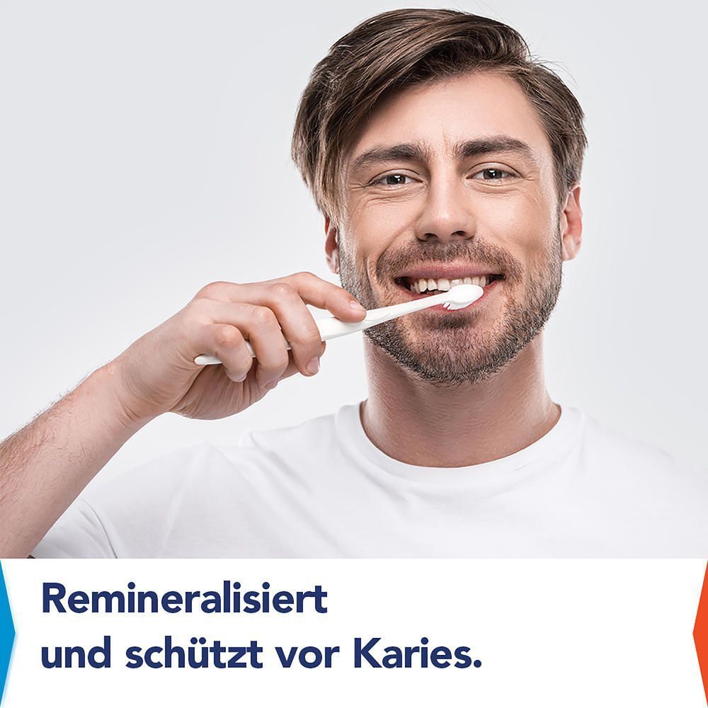 Mann putzt sich lächelnd die Zähne mit einer Zahnbürste, die Remineralisierung und Kariesschutz.