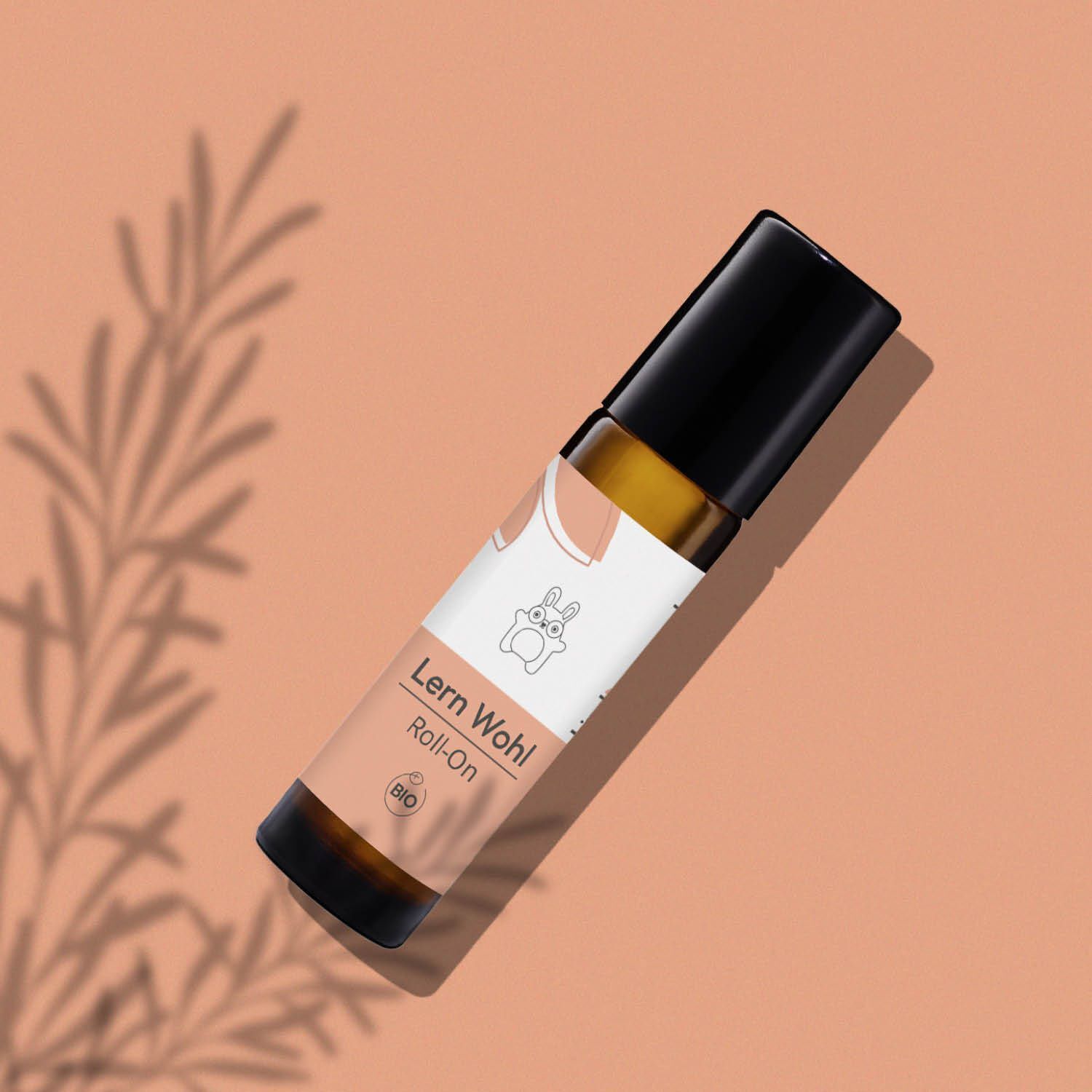 Ein schräger kindgesund® Bio-Lern Wohl Roll-On auf einem pfirsichfarbenen Hintergrund mit Schatten.