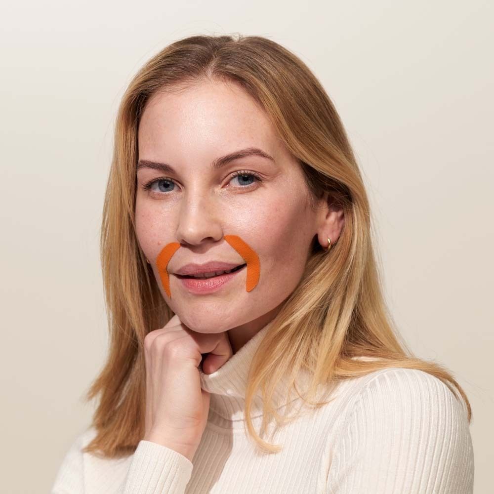 Eine Frau mit zwei orangefarbenen Mund Patches um den Mundbereich.
