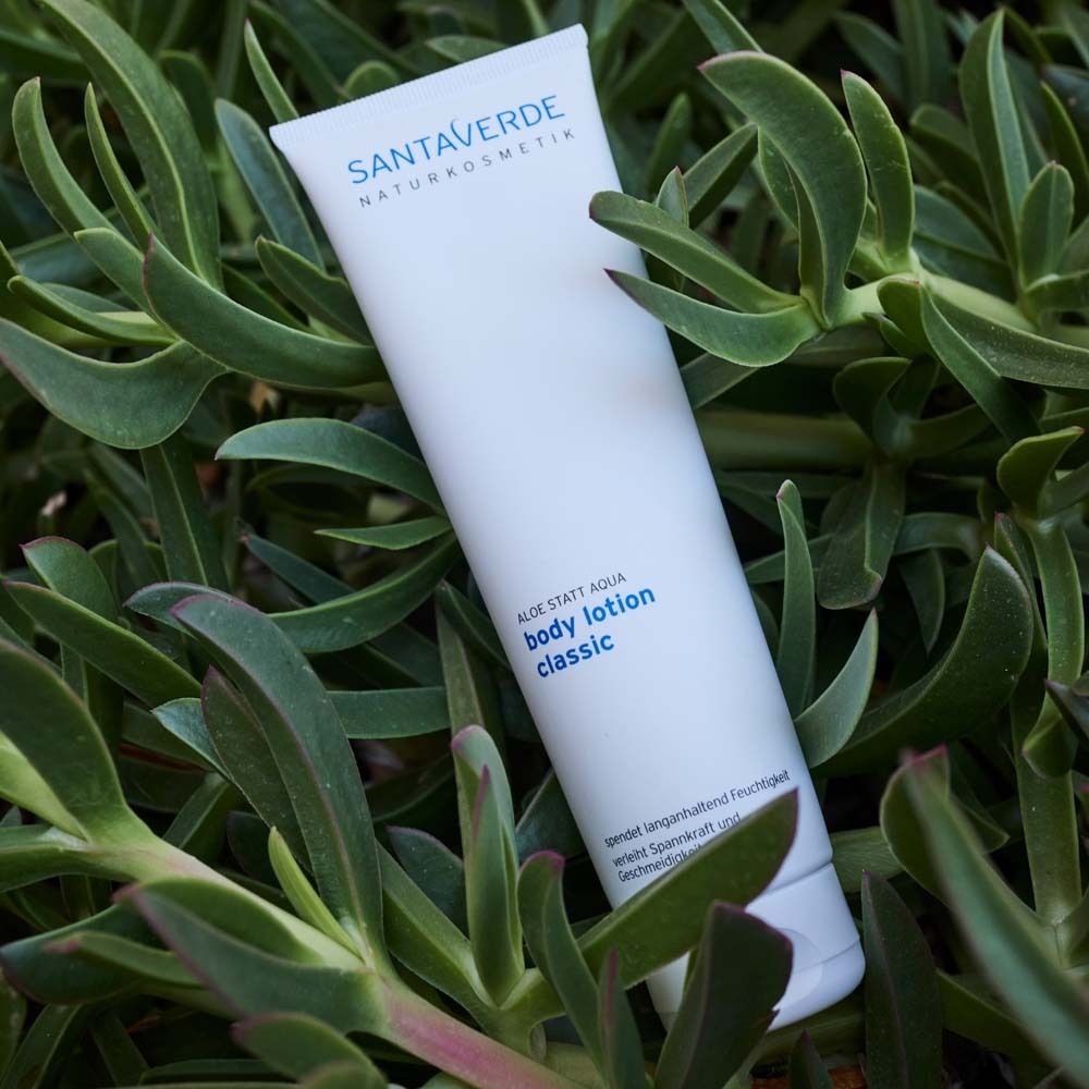 Weiße Tube mit SANTAVERDE-Logo und Aufschrift body lotion classic. Auf Blättern platziert.