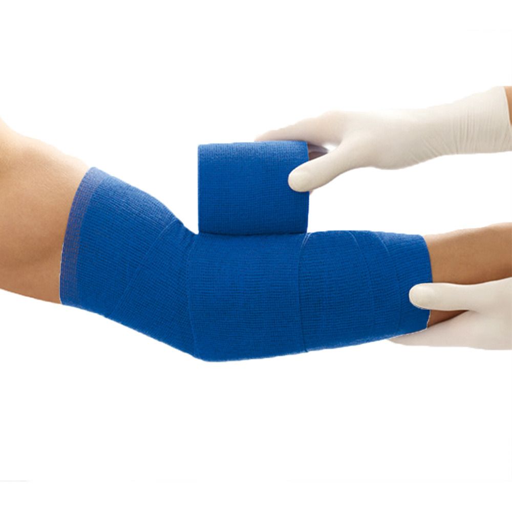 Blaues Verbandmaterial wird an einem Arm angebracht. Eine Hand in einem weißen Handschuh hält die Rolle. Der Arm ist teilweise verbunden.