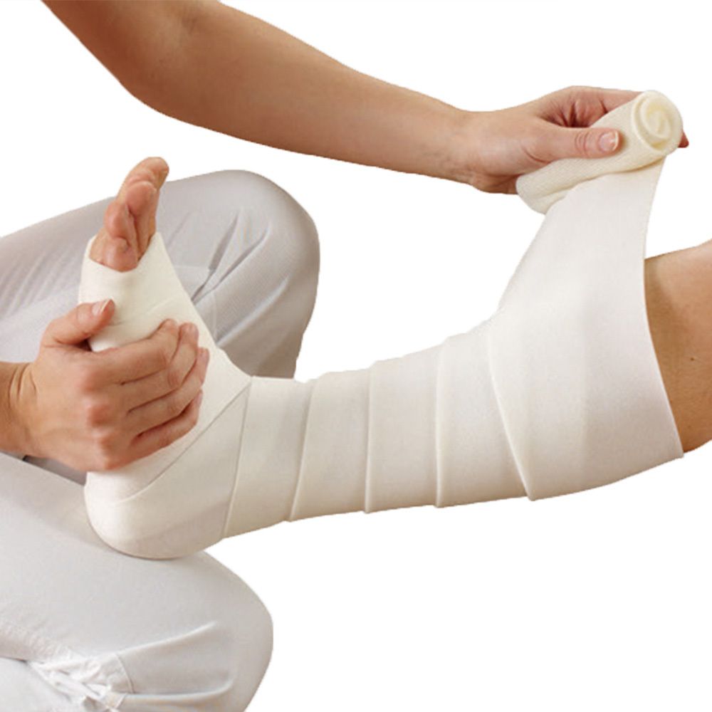 Fußverband mit weißem Verbandmaterial. Hände wickeln den Verband um den Fuß und das Bein.