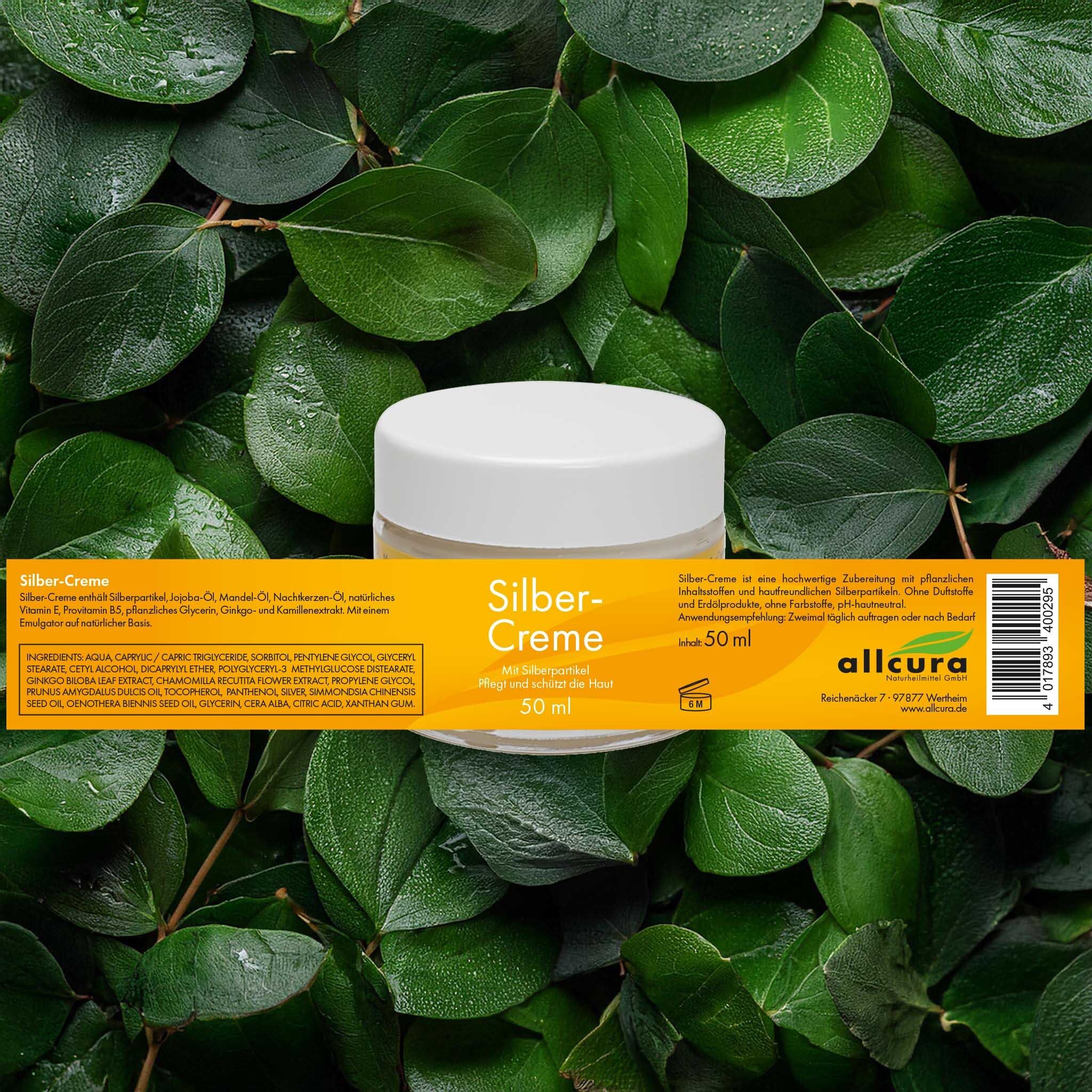 Glasbehälter mit weißem Deckel, umgeben von grünen Blättern. Gelbes Etikett mit Text: Silber-Creme, 50 ml.