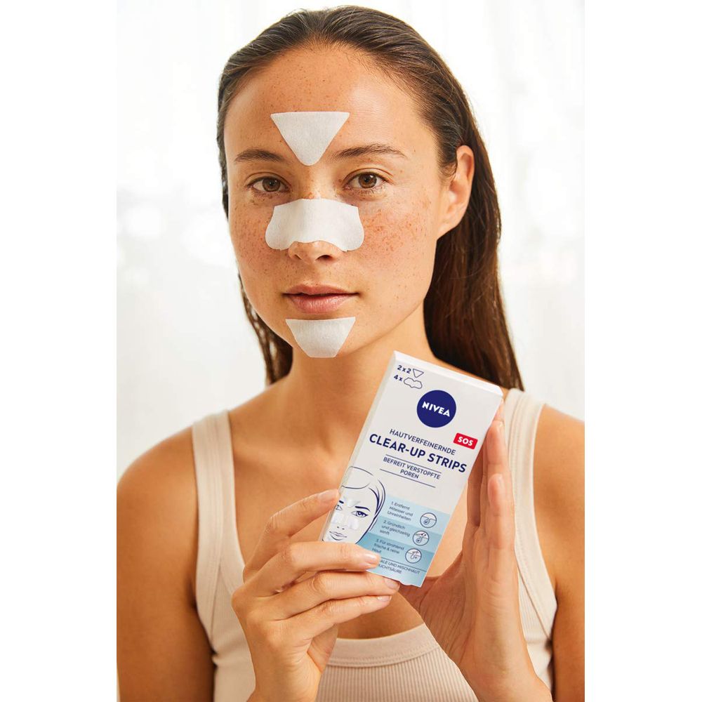Frau mit NIVEA Clear-Up Strips auf Nase, Stirn und Kinn. Sie hält die Produktverpackung.