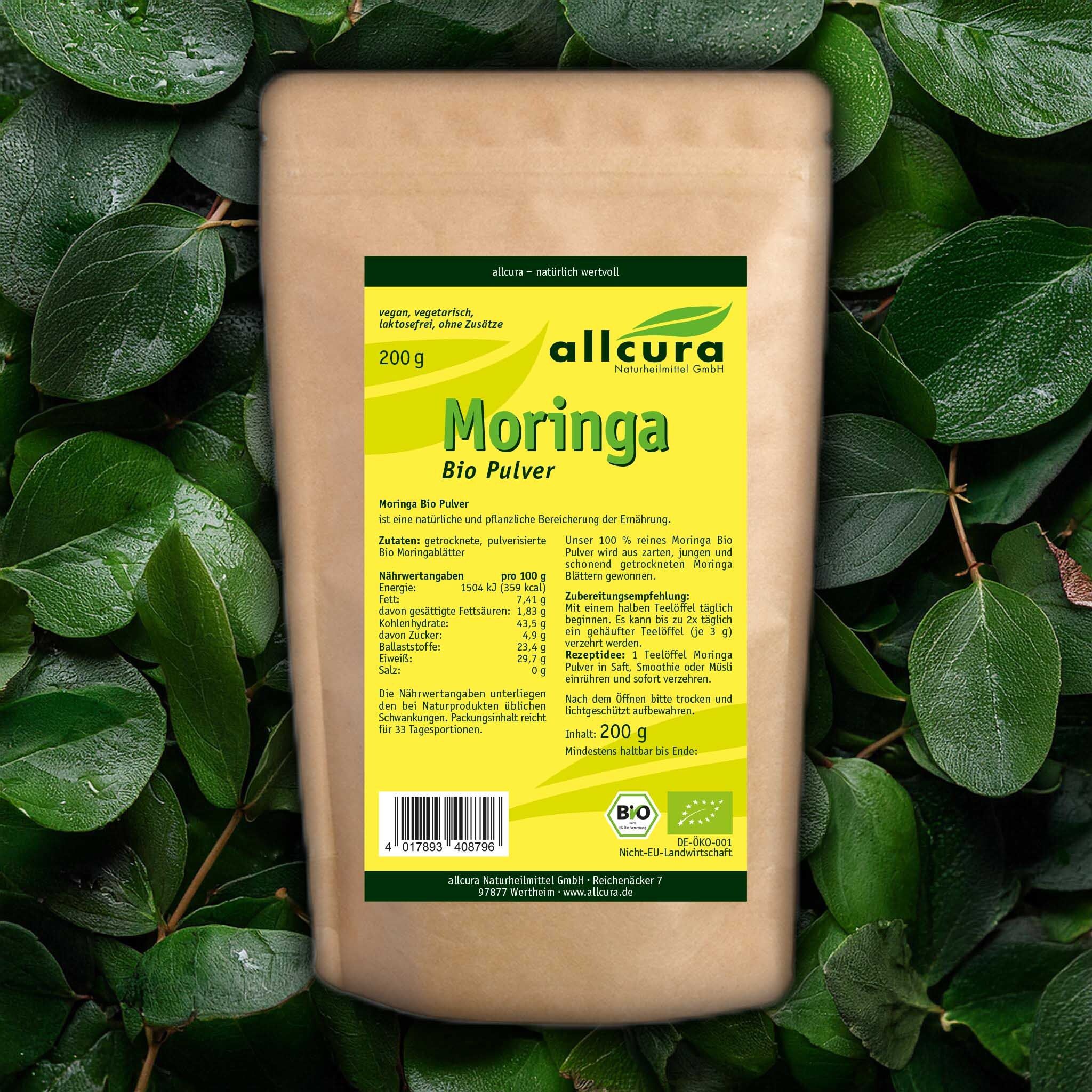 Brauner Beutel mit gelbem Etikett. Aufschrift: allcura Moringa Bio Pulver, 200 g. Bio-Siegel. Hintergrund: grüne Blätter.