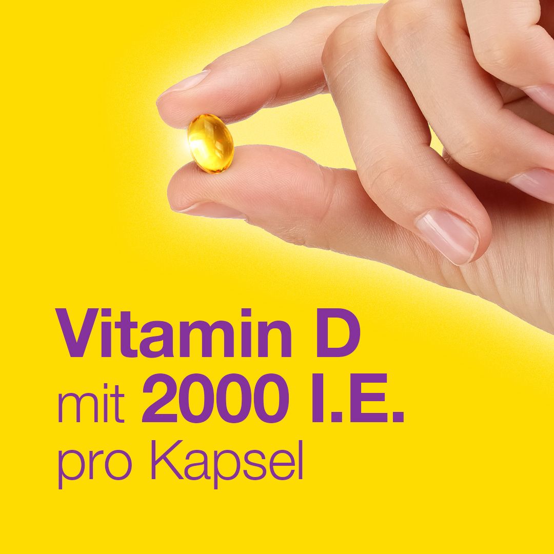 Hand hält eine gelbe Kapsel. Text: Vitamin D mit 2000 I.E. pro Kapsel.