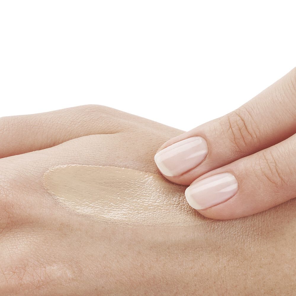 Hand mit aufgetragener Sonnencreme. Farbton: hellbeige.