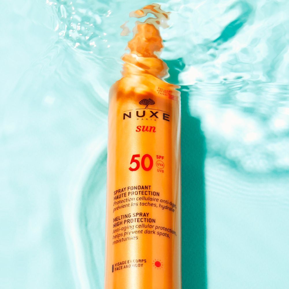NUXE Sun Sonnenschutzspray LSF 50 in Wasser. Goldene Flasche mit Sprühkopf. Text: Spray Fondant Haute Protection.