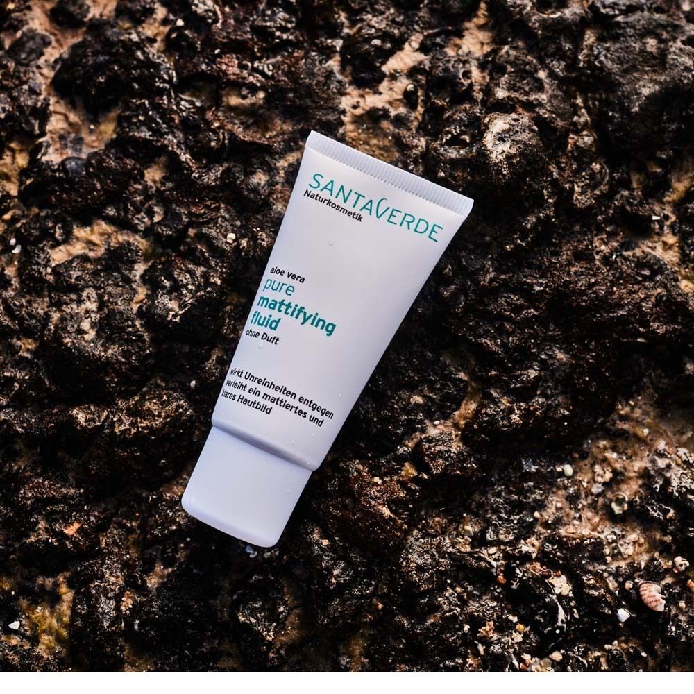 Tube SANTAVERDE pure mattifying fluid auf rauer, dunkler Oberfläche. Text: Aloe vera, ohne Duft.