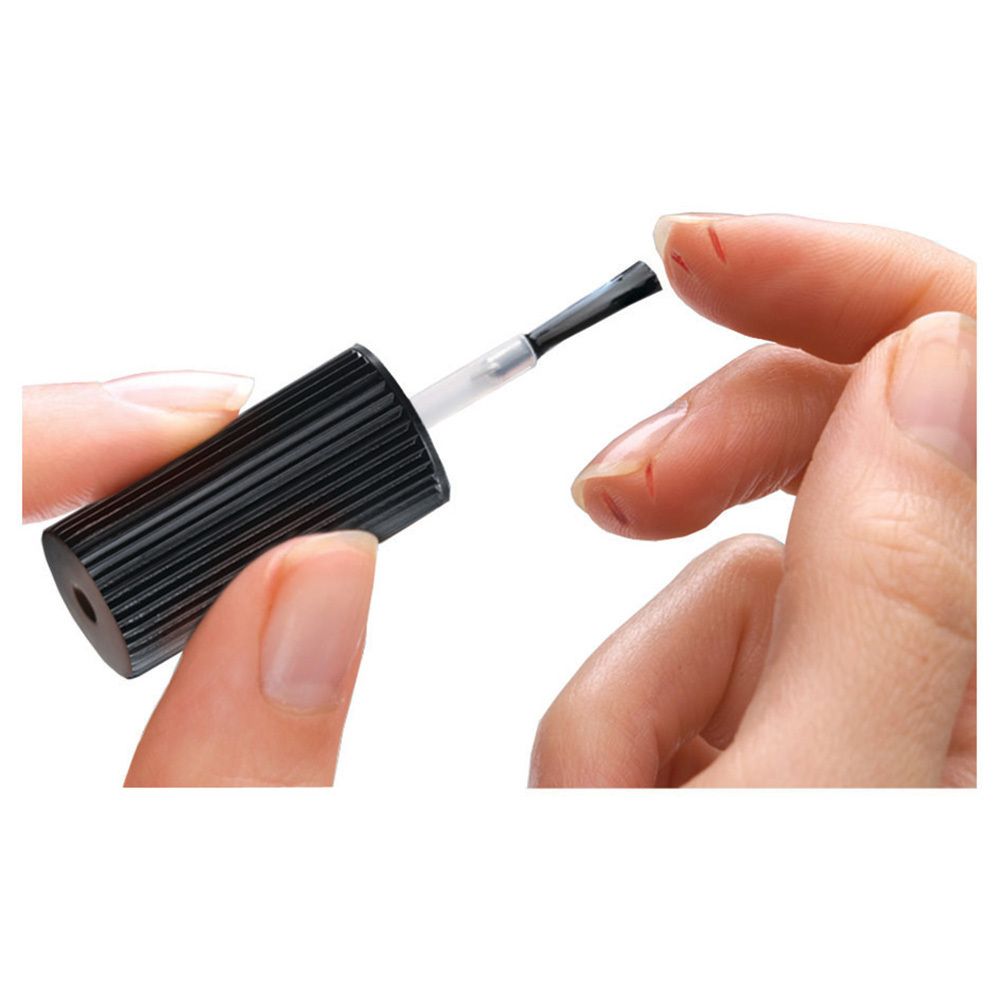 Hand mit Pinsel. Pinselspitze berührt Haut. Schwarzer Pinselgriff, transparente Flüssigkeit.