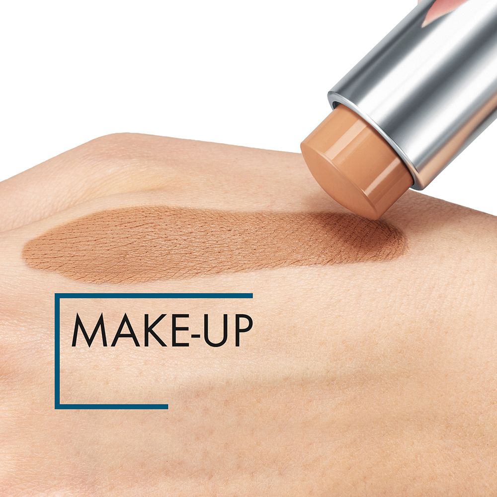 Make-up-Stick auf Hand aufgetragen. Farbton auf Haut aufgetragen. Schriftzug MAKE-UP in blauem Feld.
