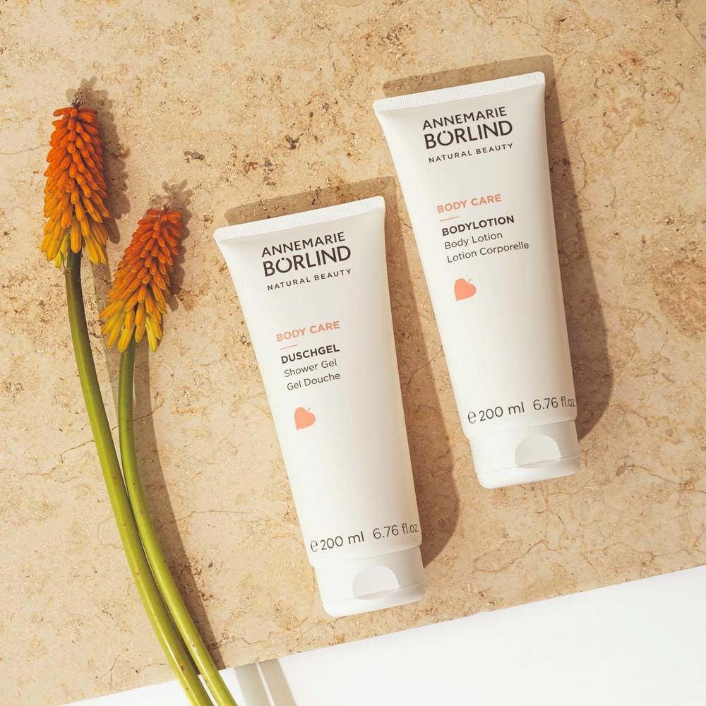 Zwei Tuben und eine Blüte. Text: ANNEMARIE BÖRLIND, BODY CARE, Duschgel und Bodylotion. 200 ml.