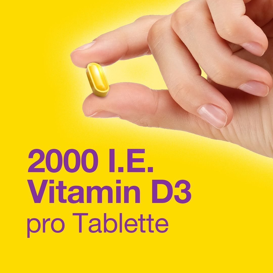 Hand hält gelbe Kapsel. Text: 2000 I.E. Vitamin D3 pro Tablette.