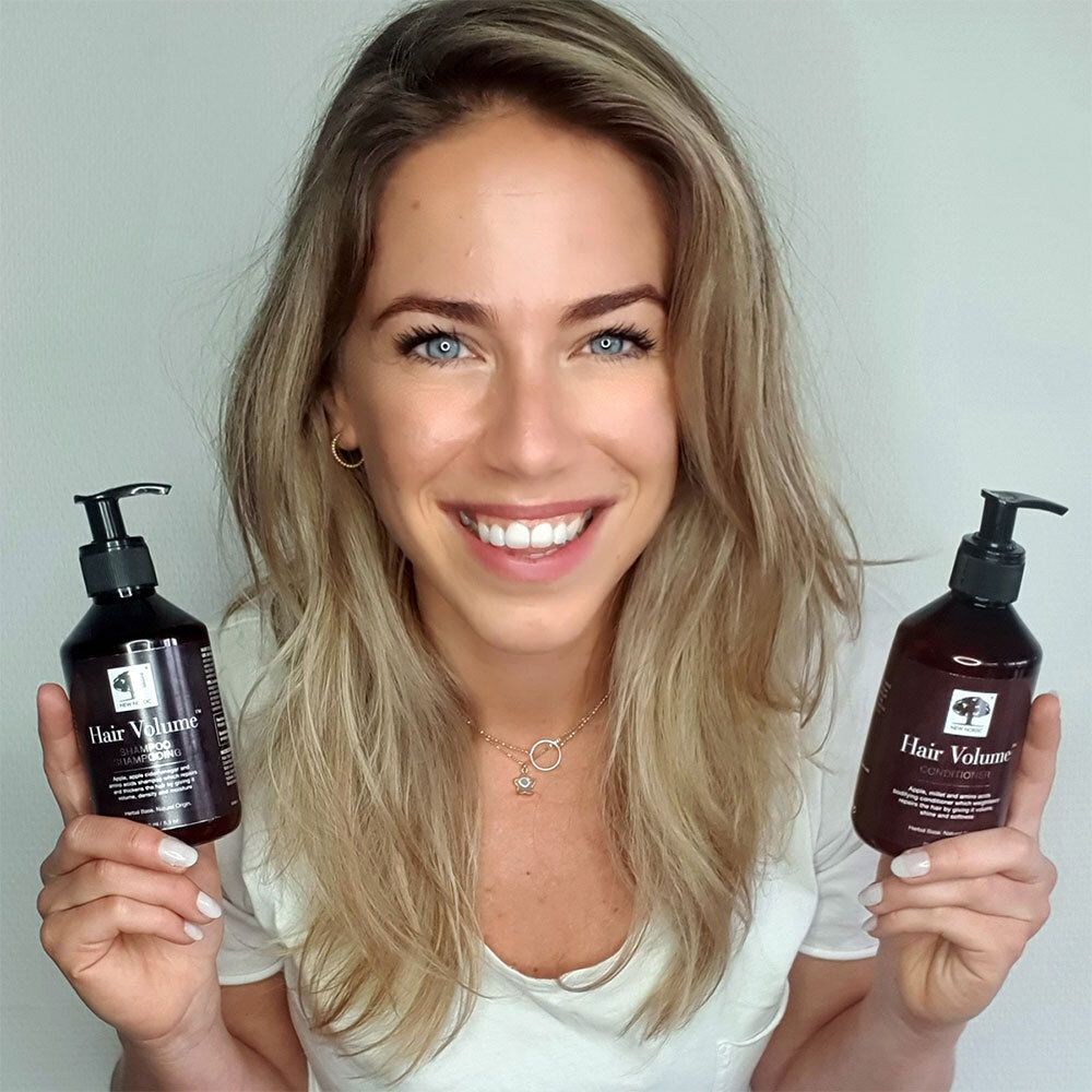 Frau hält zwei Flaschen mit schwarzem Pumpverschluss. Aufschrift: Hair Volume Conditioner.